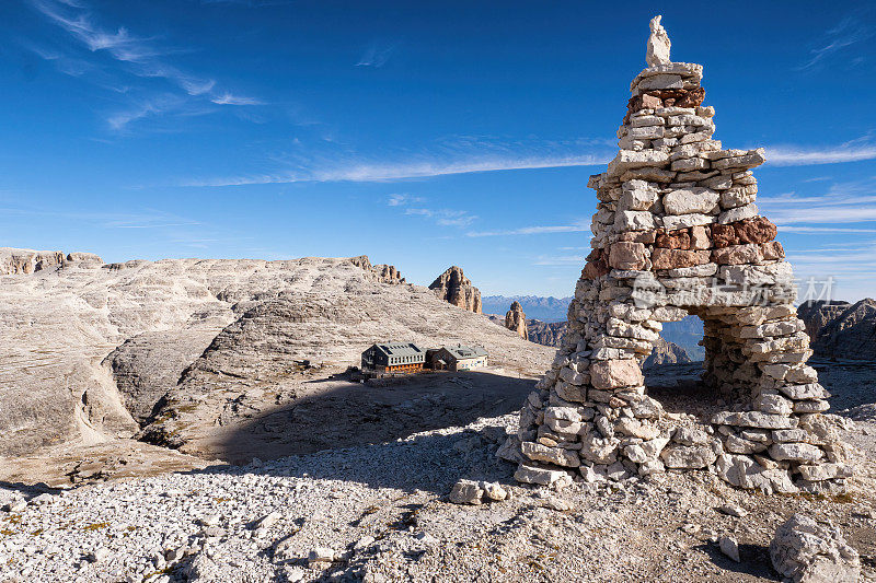 白云石，意大利阿尔卑斯山。前景中石头上的土堆和背景中的rifugio Boe小屋。去皮兹波徒步旅行。萨拉地块